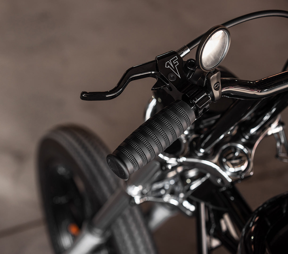 Close-up of 1FNGR easy pull clutch lever with brand logo on perch a blurred background